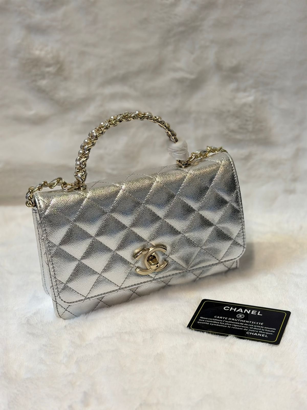 Chanel handbag, likely a quilted classic flap bag or a similar model featuring the brand's iconic interlaced chain strap and logo.